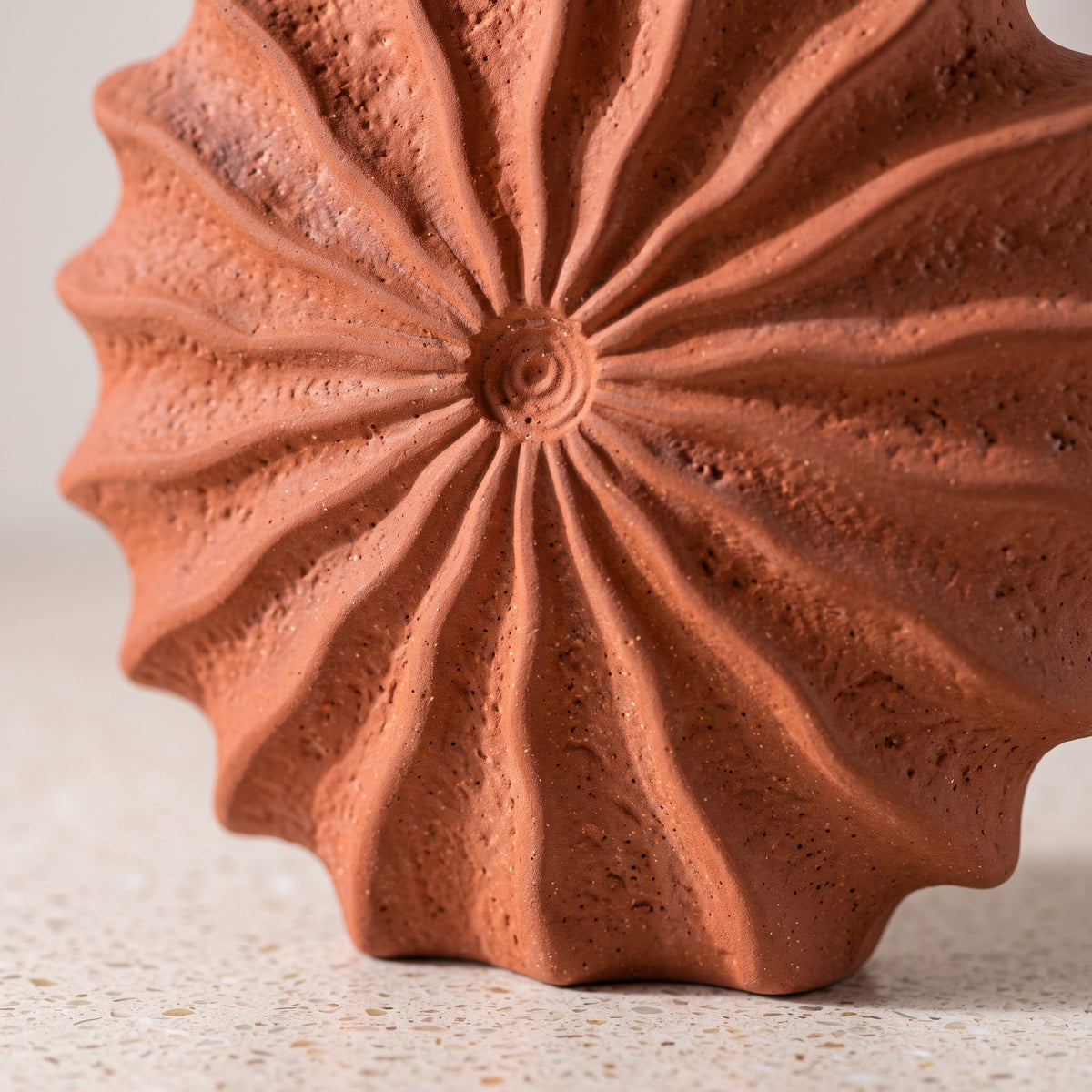 Close-up of the radiating ridges and matte texture of the sunburst vase